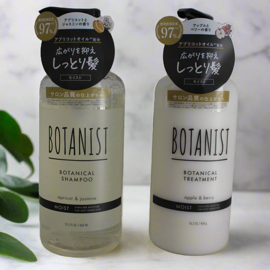 Two bottles of Botanist shampoo and treatment set on a light background with green leaves.