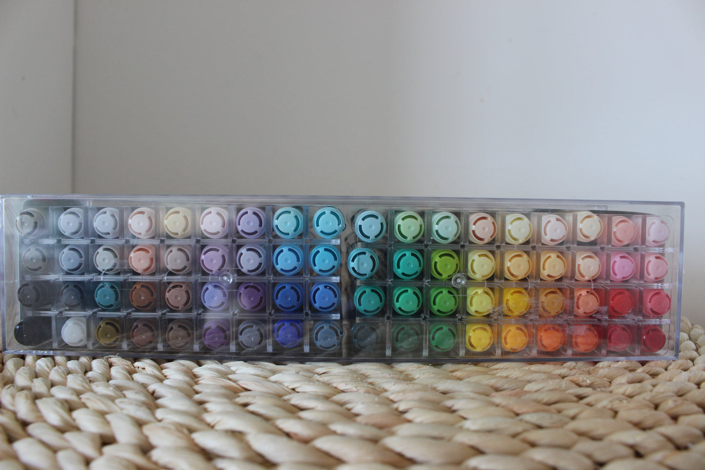 Set of colorful COPIC markers in a clear holder on a woven surface