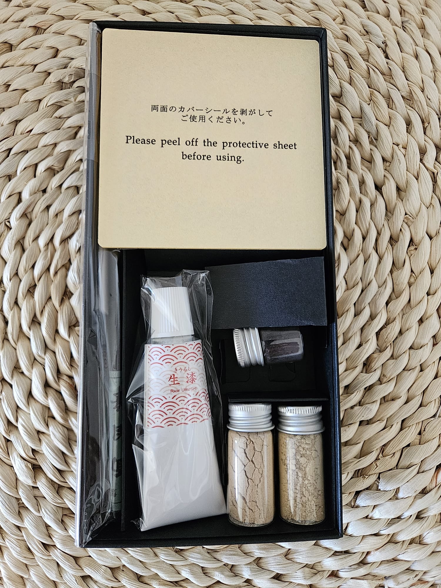 Kitntsugi kit set for beginners featuring a black box, instructions, ink, palette dropper, spatula, gold powder, masking tape on a purple background.